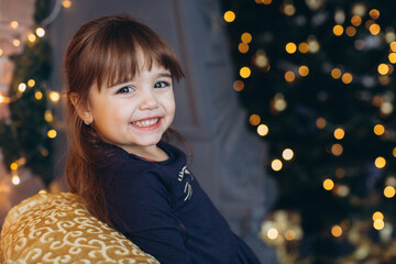 Naklejka premium Portrait of a cute little girl decorating a Christmas tree at home
