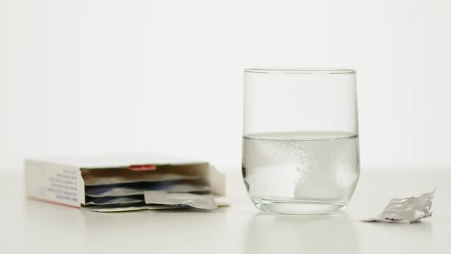 Main qui laisse tomber un cachet d&rsquo;aspirine soluble dans un verre d'eau