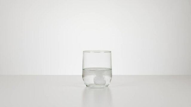 Main qui met un comprim&eacute; d'aspirine effervescent dans verre d'eau qui se dissout.