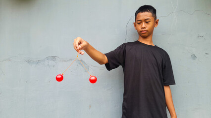 Kid holding lato-Lato. A traditional toy consisting of two heavy pendulums made of plastic and suspended by a string. Its  traditional game can be found in Indonesia. These lato-lato have been very ic - obrazy, fototapety, plakaty