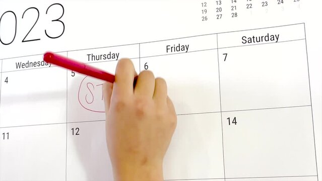 Hand writing start with a red marker on a calendar for 2023