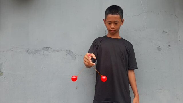 Kid holding lato-Lato. A traditional toy consisting of two heavy pendulums made of plastic and suspended by a string. Its  traditional game can be found in Indonesia. These lato-lato have been very ic