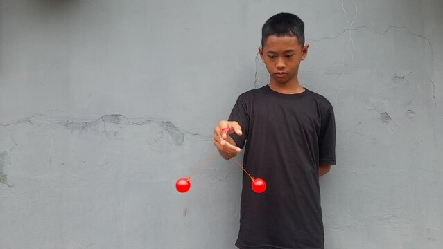 Kid holding lato-Lato. A traditional toy consisting of two heavy pendulums made of plastic and suspended by a string. Its  traditional game can be found in Indonesia. These lato-lato have been very ic