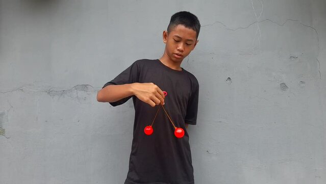 Kid holding lato-Lato. A traditional toy consisting of two heavy pendulums made of plastic and suspended by a string. Its  traditional game can be found in Indonesia. These lato-lato have been very ic