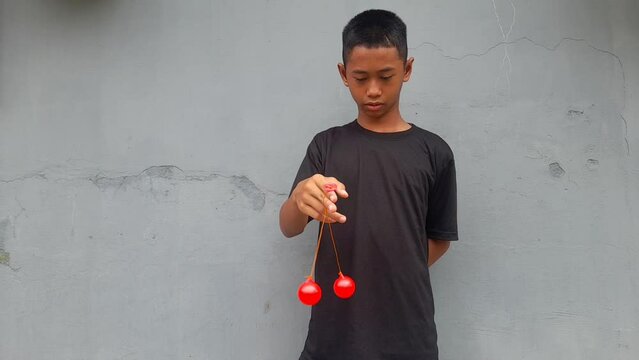 Kid holding lato-Lato. A traditional toy consisting of two heavy pendulums made of plastic and suspended by a string. Its  traditional game can be found in Indonesia. These lato-lato have been very ic