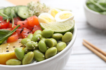 Delicious poke bowl with quail eggs, fish and edamame beans, closeup. Space for text