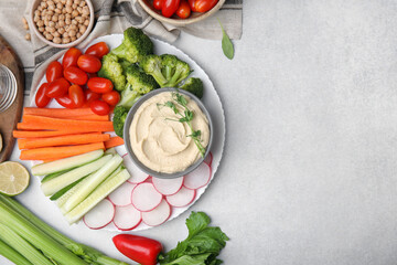 Plate with delicious hummus and fresh vegetables on light grey table, flat lay