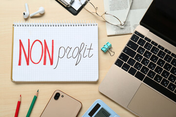 Non profit. Flat lay composition with notebook, stationery and laptop on wooden table