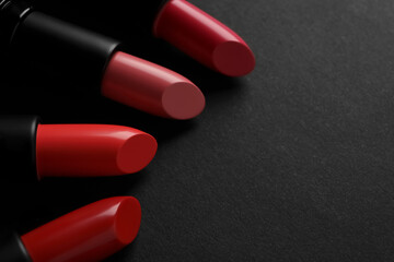 Beautiful lipsticks on black background, closeup. Space for text
