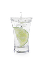 Vodka splashing out of shot glass with lime on white background