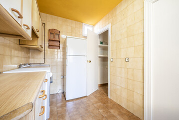 Old kitchen with similar wooden worktop, white furniture and loose appliances of the same color
