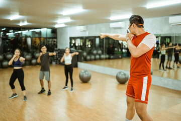 male instructor doing punching moves followed by several people during practice