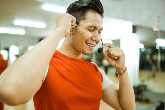 close up of instructor setting up wireless microphone getting ready before leading workout in fitness center