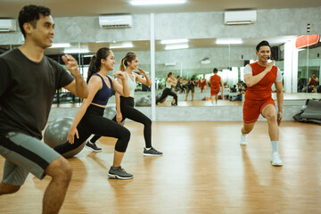 four sporty people stance while exercising together against a glass wall background