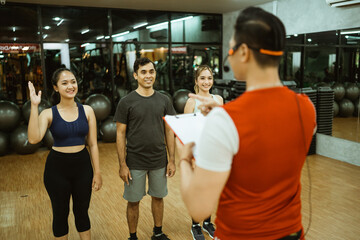 Fototapeta na wymiar Asian male instructor leading three members for group briefing before working out at the fitness center