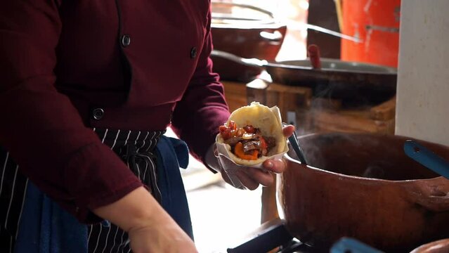 Unrecognizable woman preparing an arepa with vegetables in a restaurant. Horizontal video.
