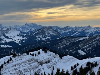 Fototapeta na wymiar Magical sunset and shy sun behind winter clouds over the Obertoggenburg region and in the Swiss Prealps, Urnäsch (Urnaesch or Urnasch) - Canton of Appenzell Innerrhoden, Switzerland (Schweiz)