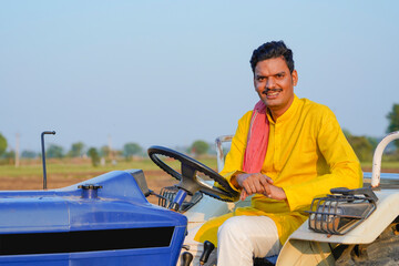 Indian farmer sitting on tractor at agriculture field.