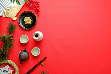 赤背景の上の日本の酒と正月飾り