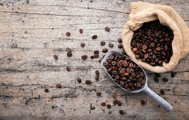 Background of dark roasted coffee beans with scoops setup on wooden background with copy space.