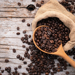 Background of dark roasted coffee beans with scoops setup on wooden background with copy space.