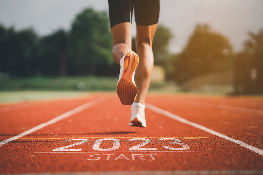 Happy new year 2023 Sport man runner running into the new year 2023. Start up of close up foot shoes jogging at stadium go to Goal of Success. People running as part of Number 2023. Sport health care.