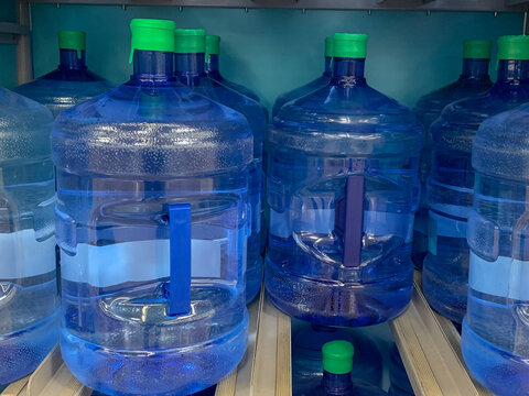 Five gallon plastic jugs of drinking water on a store display.