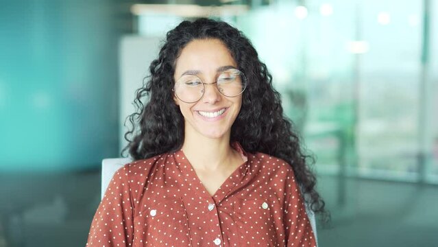 Portrait of a pleasant young female employee wearing glasses looking at camera smiling at workplace in the office Cute business woman or university student creative designer or specialist indoors