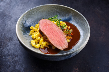 Tafelspitz roast veal slices with Swabian spaetzle served with dark beer sauce as close-up in a Nordic design bowl with copy space