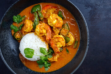 Traditional Thai kaeng phet red curry with chili and basmati rice served as top view in a Nordic design bowl