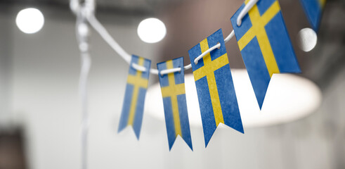 A garland of Sweden national flags on an abstract blurred background