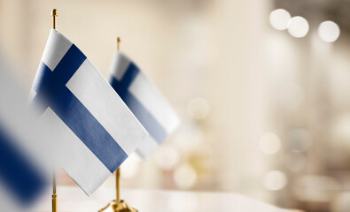 Small flags of the Finland on an abstract blurry background - 557530413