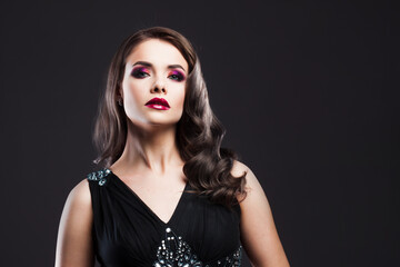 Gorgeous young brunette in a chic evening look. Scarlet lips and eye shadow, wave hair styling