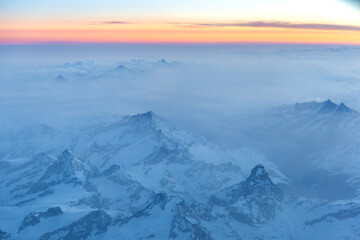 Fototapeta na wymiar The Alps at sunrise with light fog and orange sky.