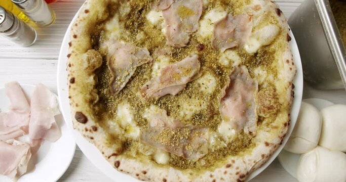 Pizza with Meat, Pesto, Cheese and Parmesan fresh out of the oven ready to eat. Delicious Italian pizza. Napoli Pizza. Food Service on white table and ingredient. Tasty Pizza with Cheese and Parmesan.
