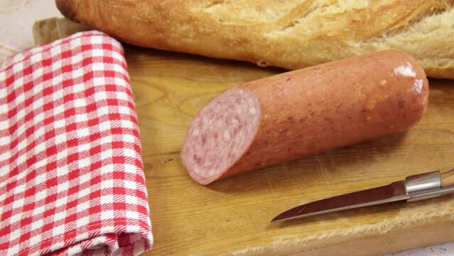 saucisson &agrave; l'ail et baguette de pain sur un planche &agrave; d&eacute;couper
