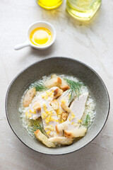 Chicken soup with croutons and rice served in a grey bowl, vertical shot on a beige stone background