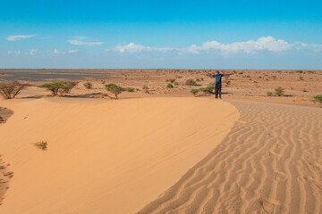 Fototapeta na wymiar A man walking on a sand dune at North Horr Sand Dune in Marsabit County, Kenya