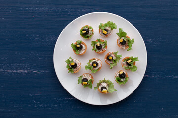 Tartlets with black olive and cheese, green leaf lettuce on plate 