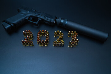 Happy new year 2023. Weapons, a pistol with a silencer and numbers from 9mm cartridges.