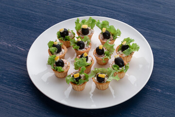 Tartlets with black olive and cheese, green leaf lettuce on plate 