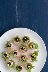 Tartlets with black olive and cheese, green leaf lettuce on plate 