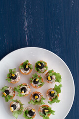 Tartlets with black olive and cheese, green leaf lettuce on plate 