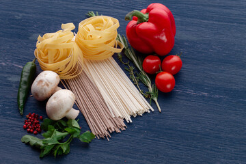 Pasta with vegetables on wood background. Ingredients for pasta