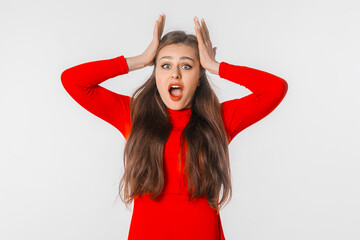Beautiful shocked and surprised woman with open mouth. Amazed girl holds head by hands, stand over...