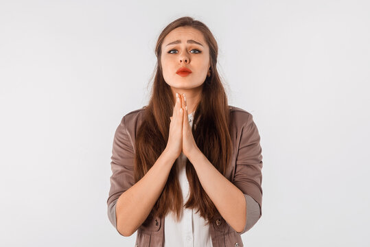 Please. Lovely young woman showing begging gesture, asking for favour, standing over white background. Religious girl praying with calm face, having hope for better future