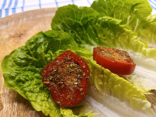 Tomate mit Kräutern und Salat auf einem Holzteller