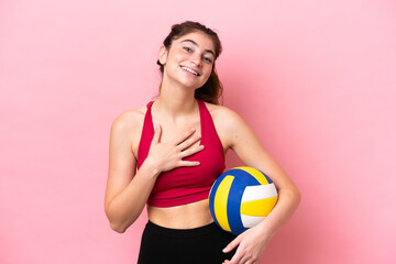 Young caucasian woman playing volleyball isolated on pink background smiling a lot