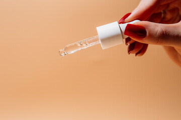 Woman hand holding pipette with collagen moisturizing hyaluron serum and drops the clear serum