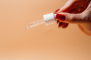 Woman hand holding pipette with collagen moisturizing hyaluron serum and drops the clear serum
